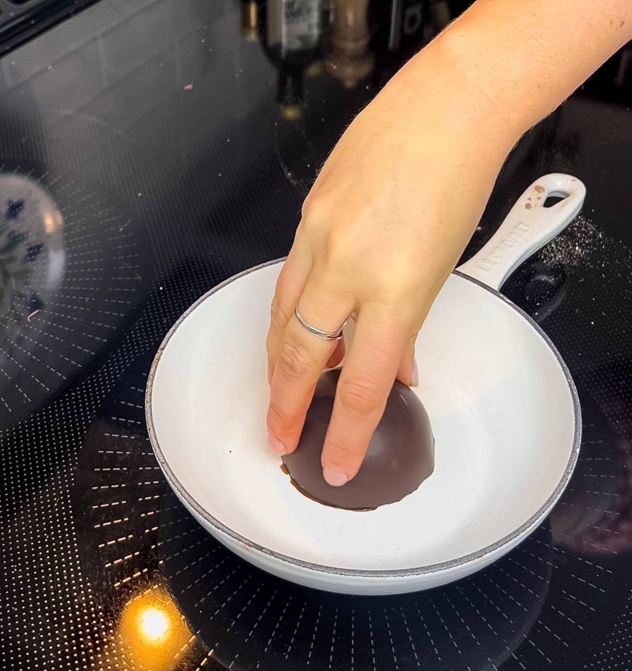 Person melting the rim of a chocolate half dome on a warm pan.