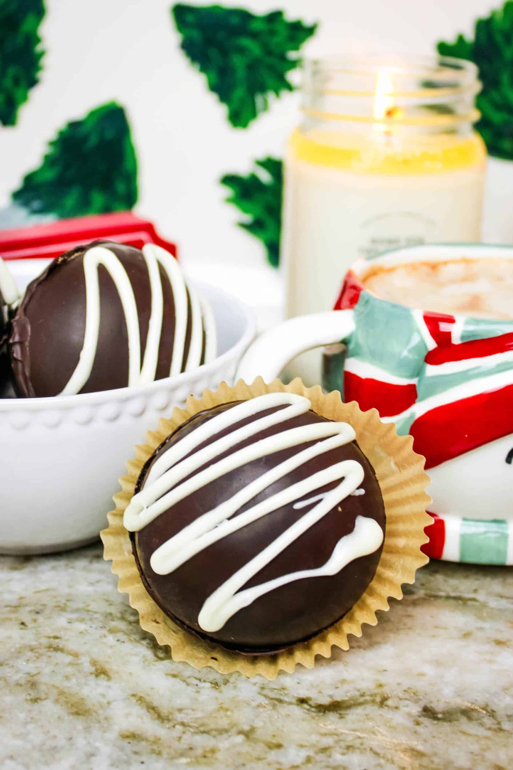 Hot cocoa bomb sitting next to a mug and bowl with more hot chocolate bombs.