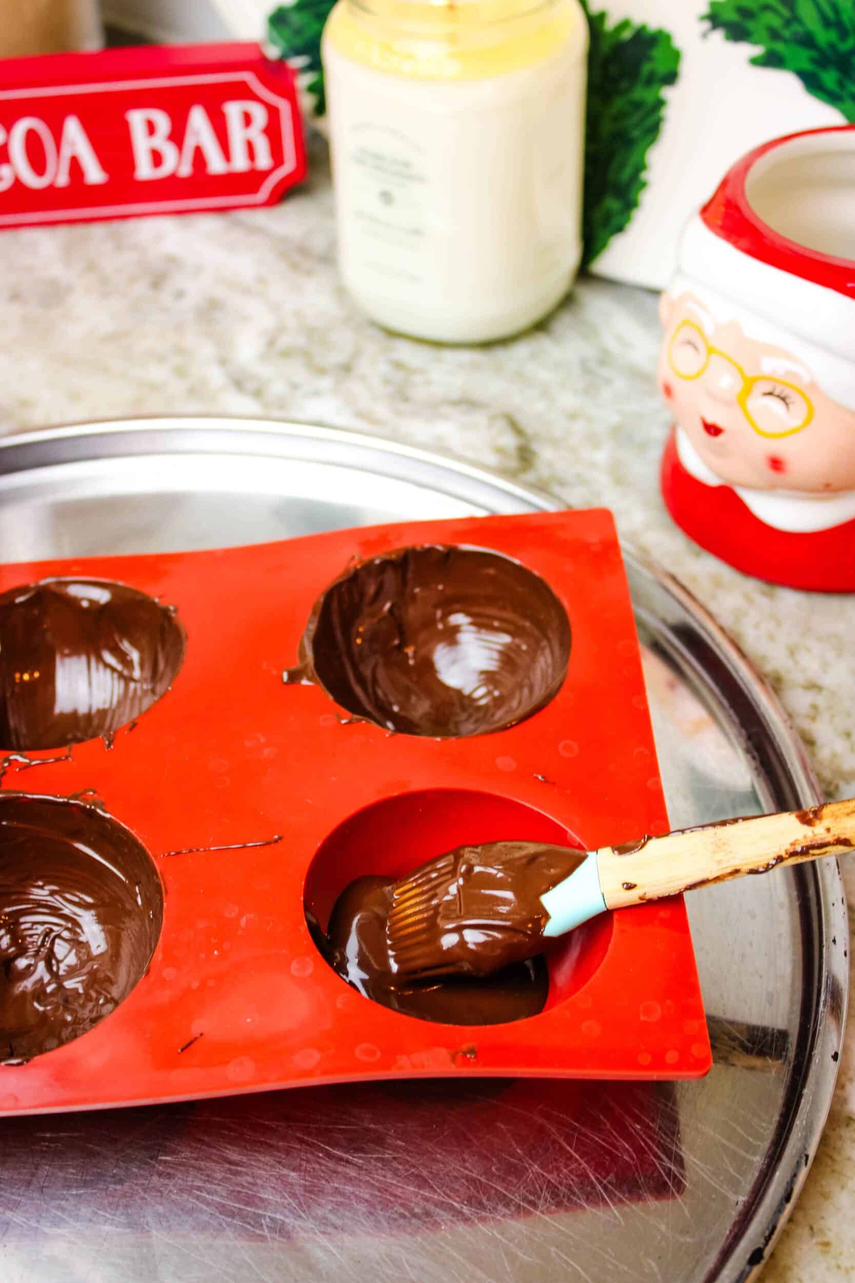 Melted chocolate being painted into silicone cocoa bomb molds.