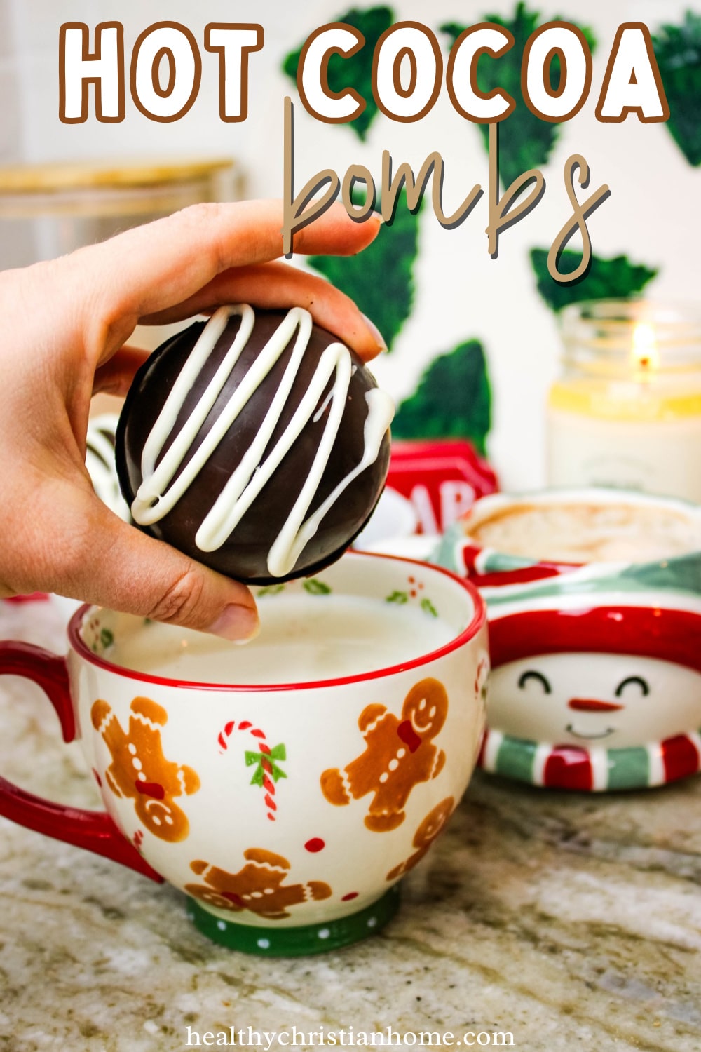 Hand holding a hot chocolate bomb, dropping it into a Christmas mug of hot milk.