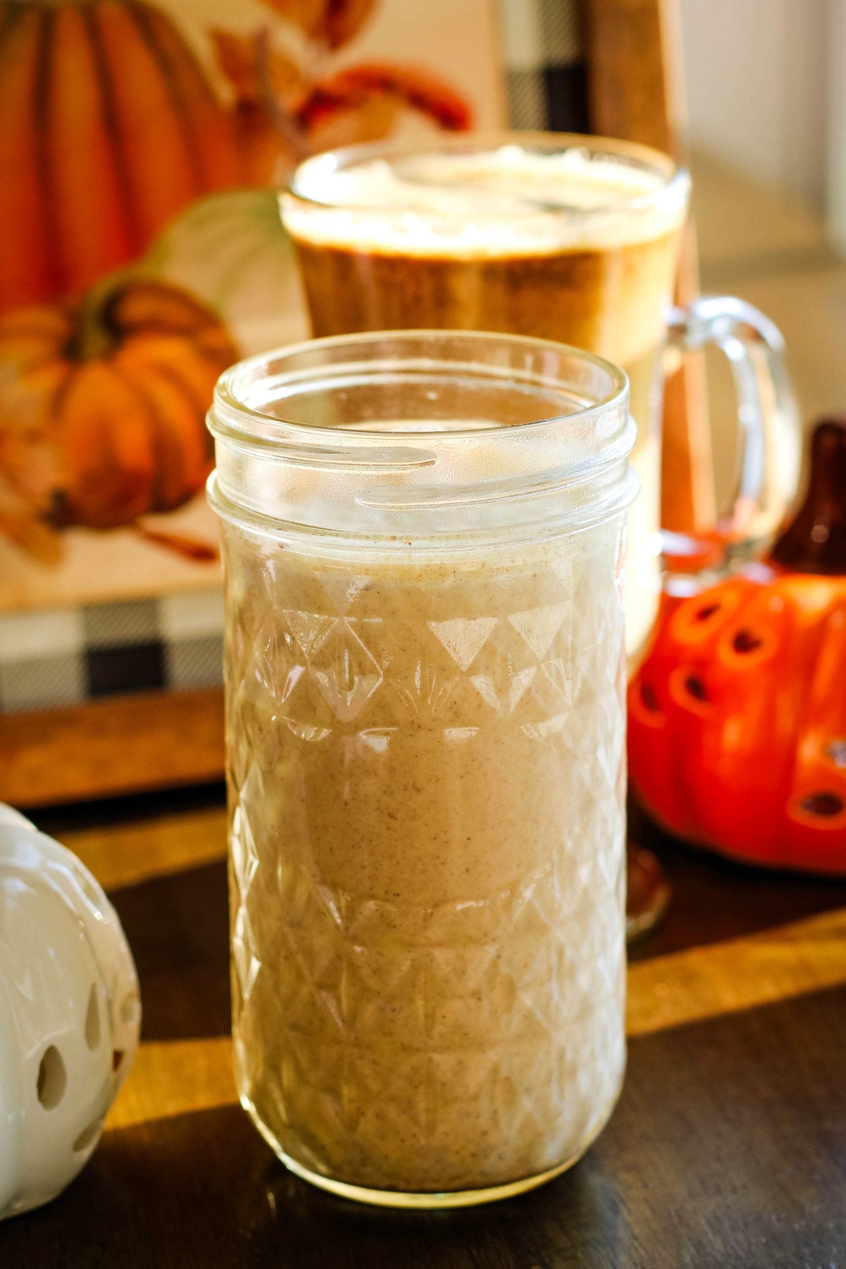 Healthy pumpkin spice creamer in a glass jar next to a ceramic pumpkin.